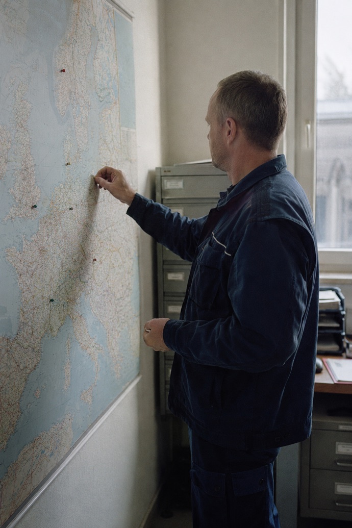 An employee in work clothing marks regions on a map of Europe in the office